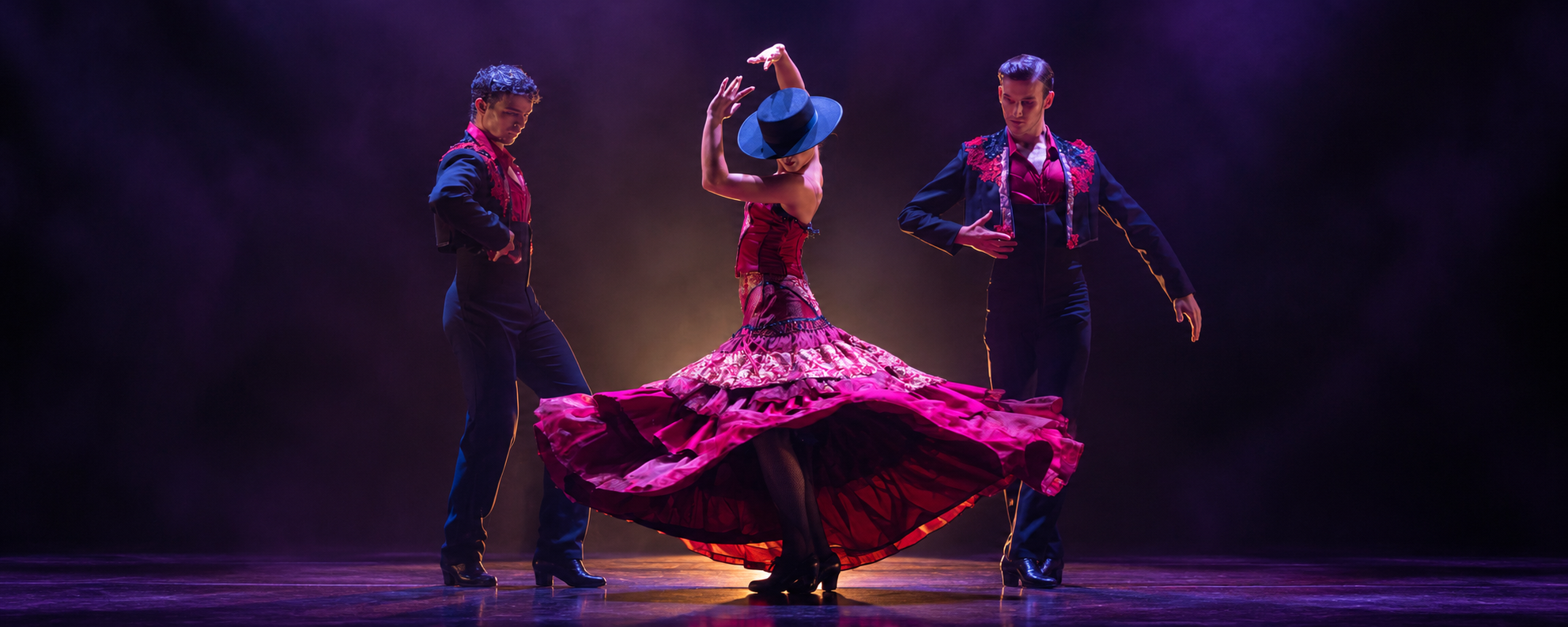 Escena de danza española con tres intérpretes e iluminación en tonos violetas y magenta